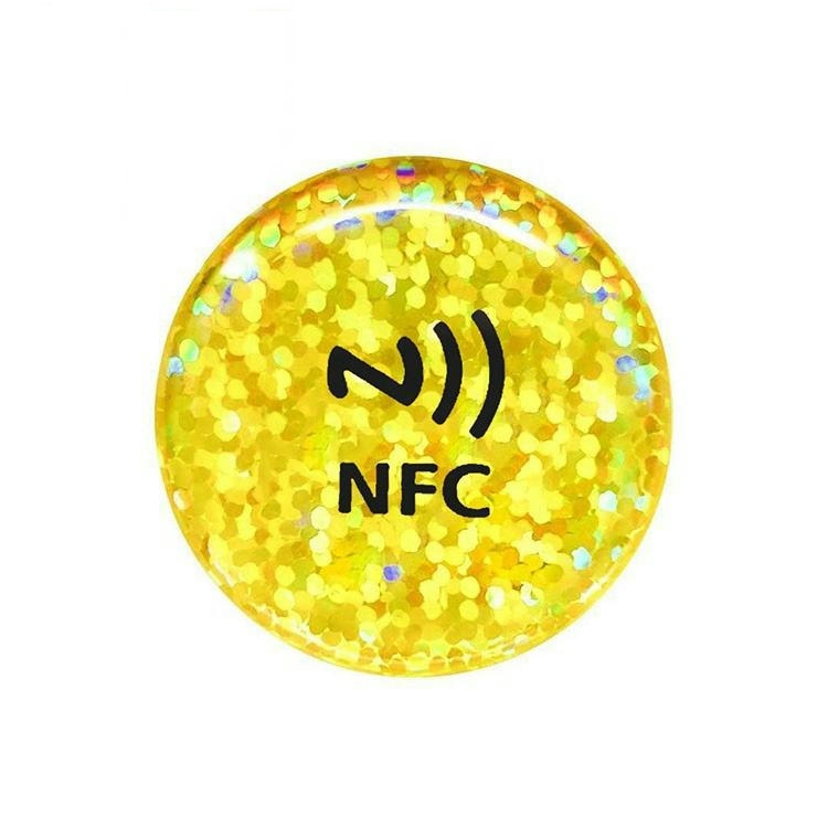 Hoge veiligheid NFC epoxy sticker getoond als een gouden glitter ronde koepel tag met NFC merk voor hoogwaardig merk authenticatie en promotie.