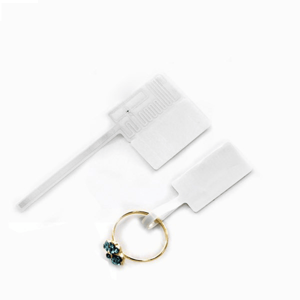 Twee RFID-sieradenlabelvoorbeelden worden met een ring weergegeven om te laten zien hoe de tag aan kleine waardevolle items wordt bevestigd.