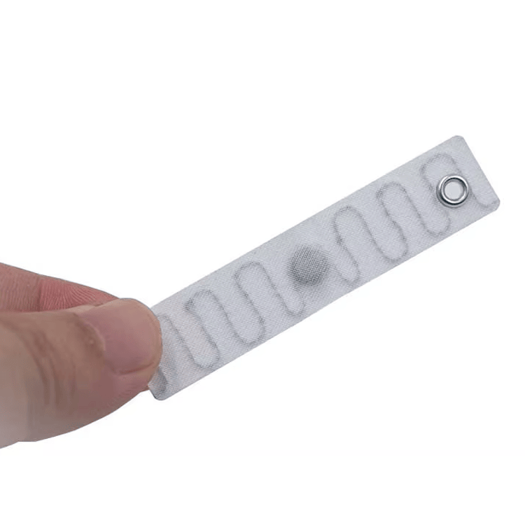 Hand-vastgehouden weergave presenteert Polyester RFID Wasserij Tags T7015-3 om de slanke flexibele label vorm voor naaien in ziekenhuislinnen te tonen.
