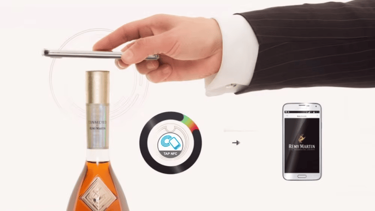 Deze afbeelding toont een telefoon boven een flessenhalsetiket als demonstratie van NFC-toegang voor drankverificatie via aantikken.