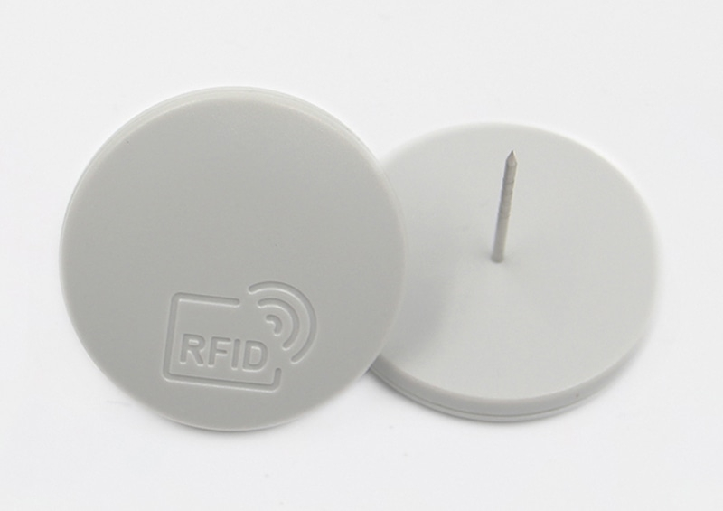 Close-up van de witte SVD34-1 RFID-retailtag naast de bijpassende pindisc voor herbruikbare kledingbeveiliging.